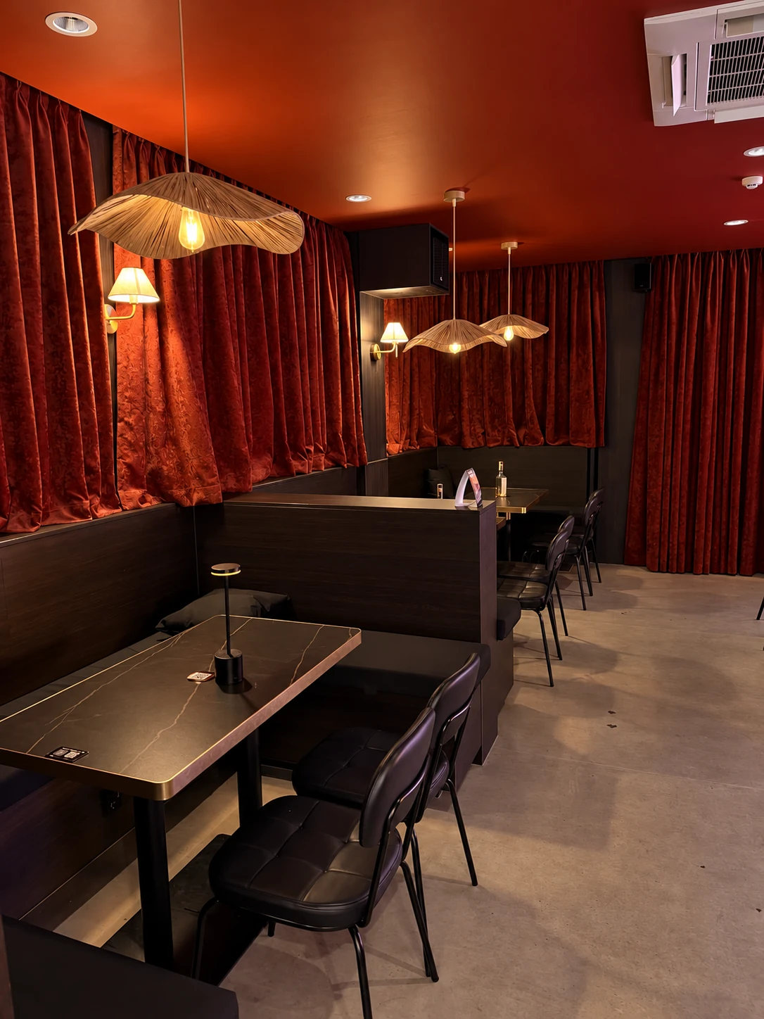 Jaya’s tables beside red curtains and warm woven lamps